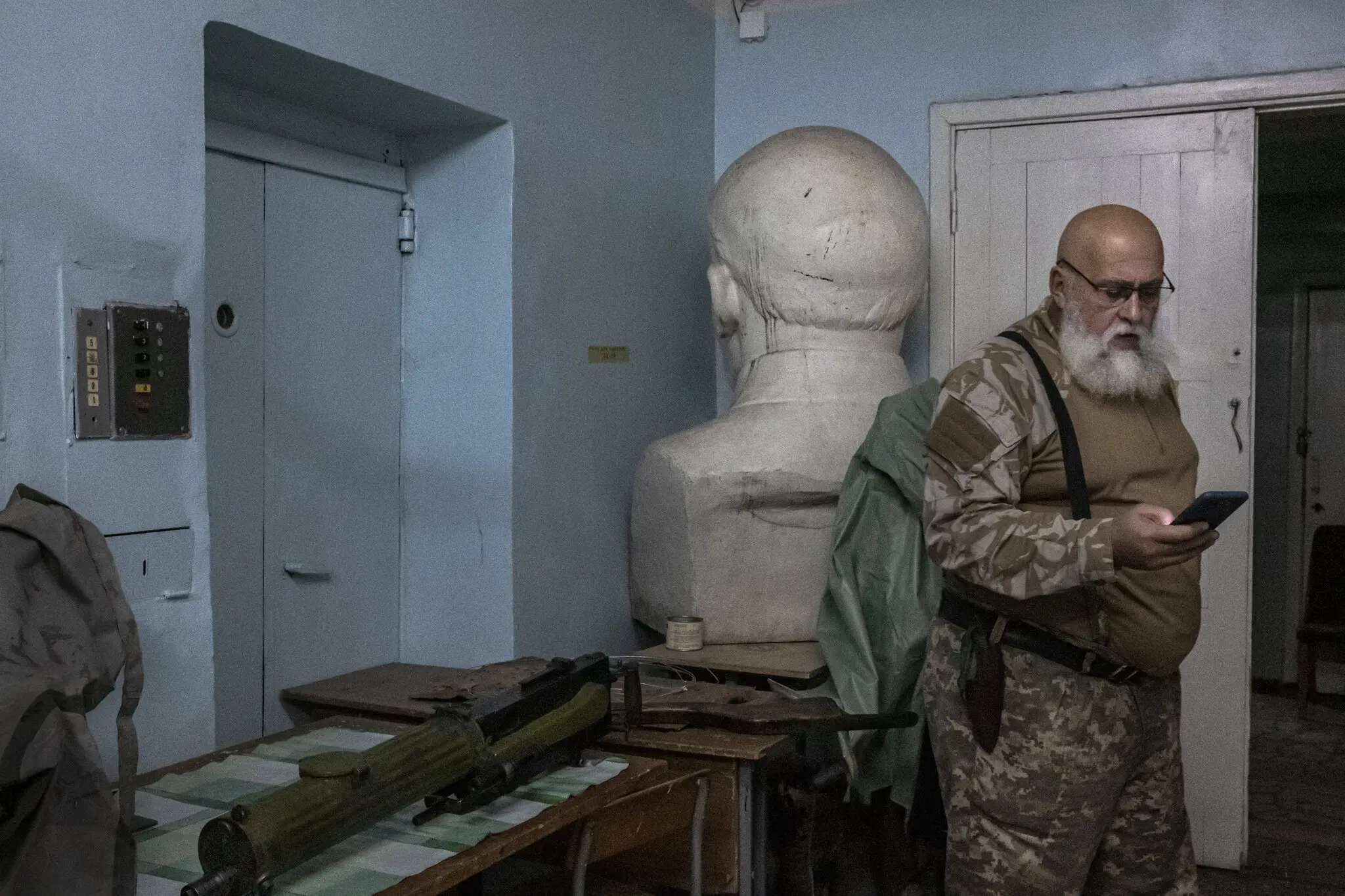 Кулемет Максим часів Другої світової війни (ліворуч) лежить на столі біля бюста Леніна, повернутого в кут на базі добровольців української протиповітряної оборони в Переяславському районі Київської області.